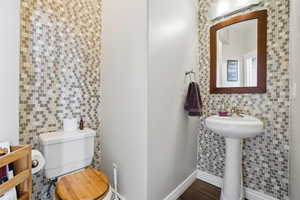 Half bathroom featuring toilet and tile walls