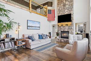 Living room featuring wood-type flooring, a fireplace, a high ceiling, and crown molding