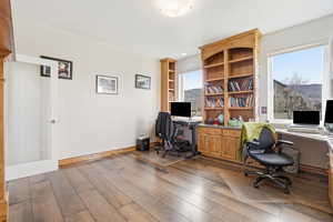 Office with dark wood-style flooring and baseboards