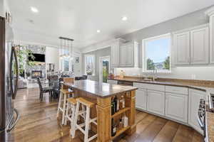 Kitchen with dark wood finished floors, white cabinets, stainless steel appliances, and dark stone countertops