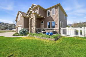 View of front of home featuring stone siding, an outdoor lounge area, a garage, and concrete driveway