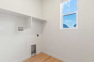 Laundry area with light wood-style flooring, hookup for a washing machine, and electric dryer hookup