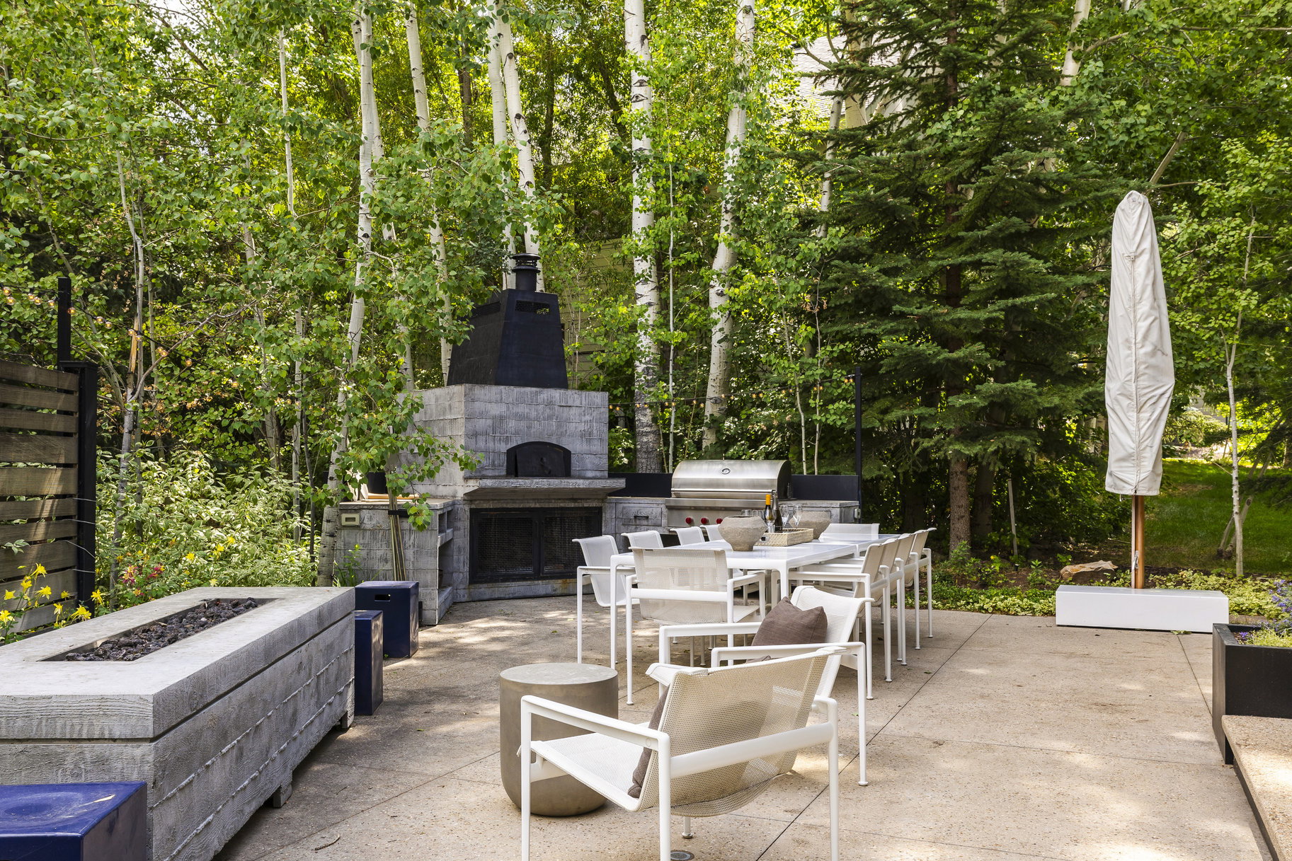 Expansive outdoor patio featuring an integrated fireplace, pizza oven, and built-in grill station