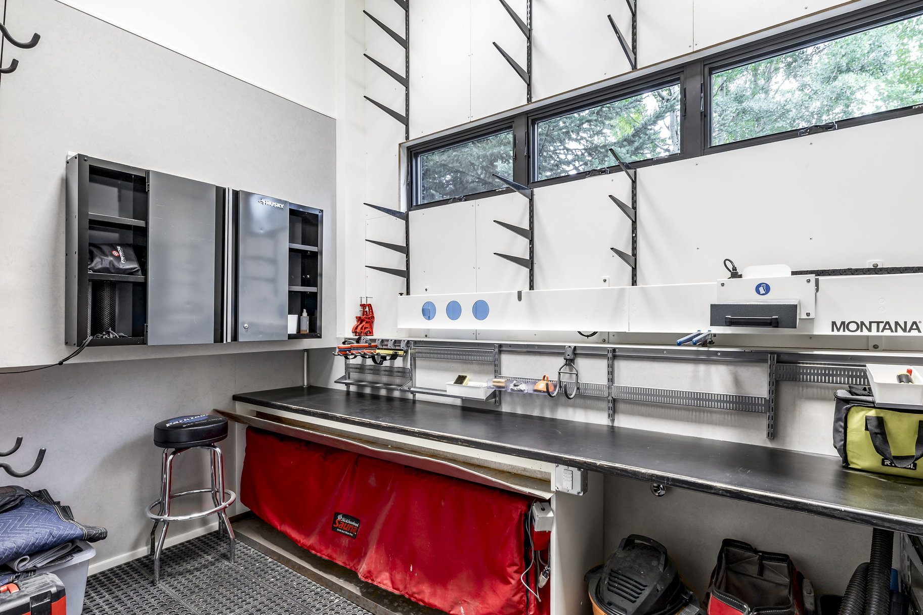 Dedicated workspace featuring a black laminate countertop, white wall paneling, and multiple built-in storage shelves
