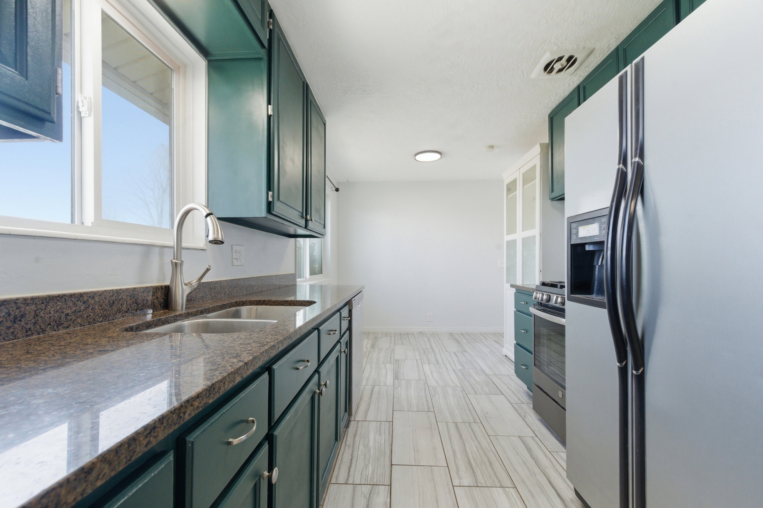 Kitchen featuring stainless steel appliances, green cabinets, and dark stone countertops