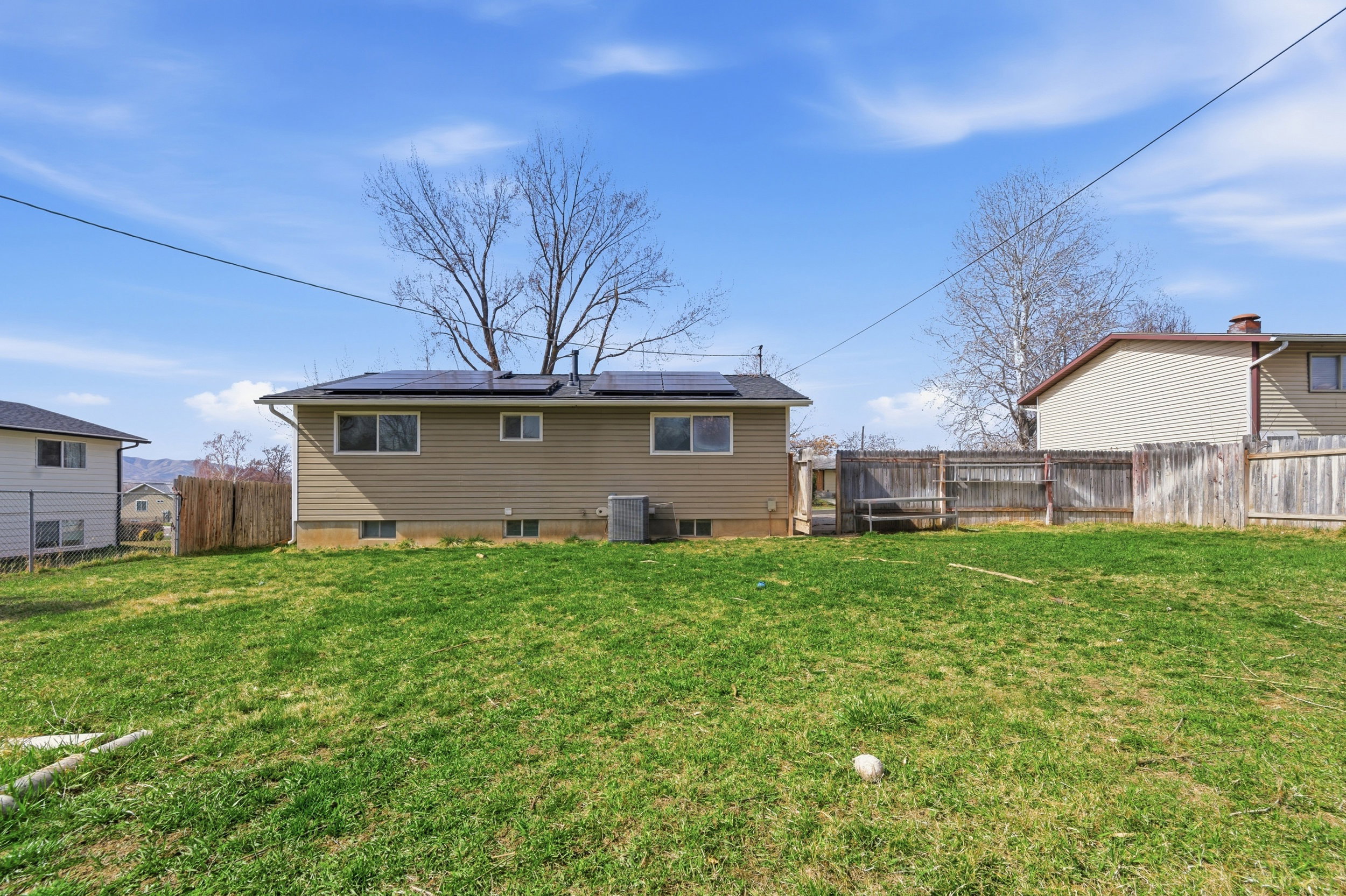 Back of house with roof mounted solar panels and a fenced backyard