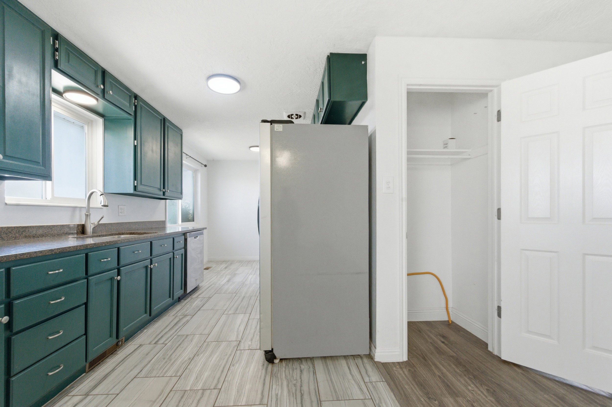 Kitchen featuring stainless steel appliances, dark countertops, green cabinets, and wood tiled floors