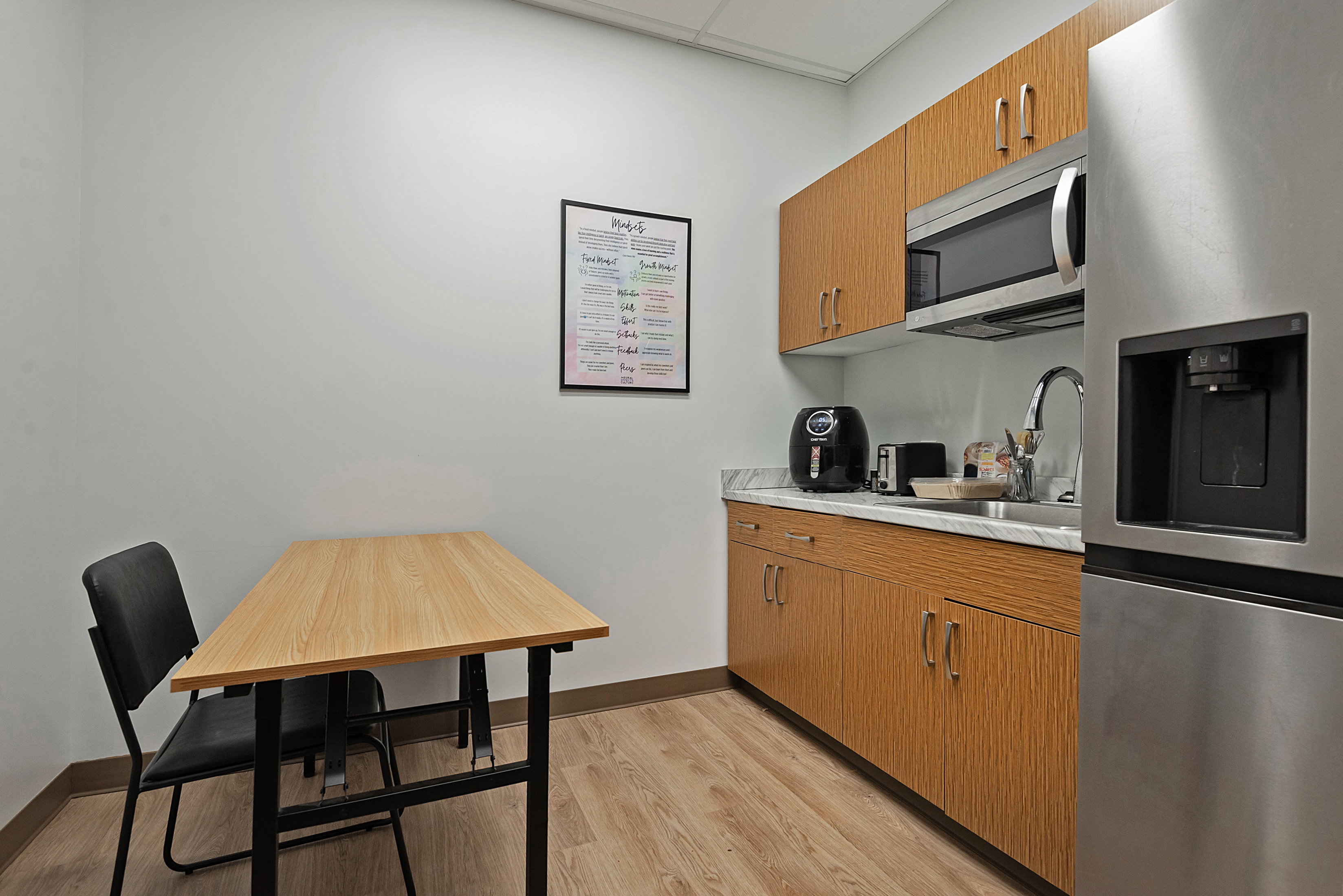 Kitchen with stainless steel appliances, wood finish cabinetry, light countertops, and a drop ceiling