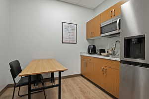 Kitchen with stainless steel appliances, wood finish cabinetry, light countertops, and a drop ceiling