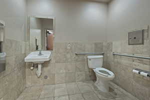 Bathroom featuring a wainscoted wall, tile patterned floors, and tile walls