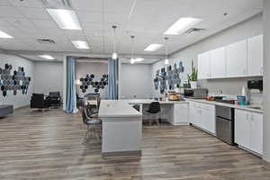 Kitchen featuring a kitchen breakfast bar, a paneled ceiling, white cabinetry, pendant lighting, and stainless steel appliances