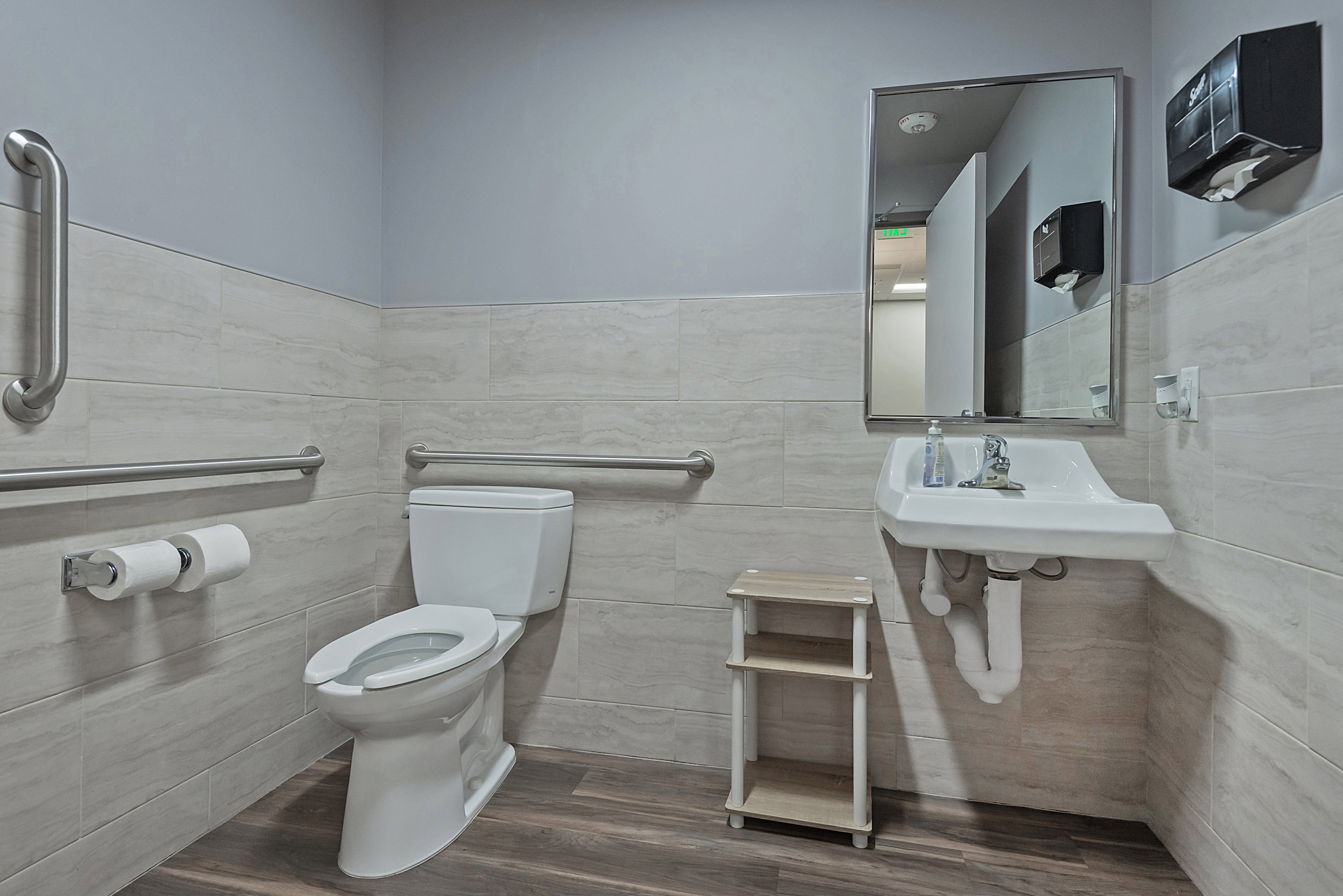Bathroom featuring dark wood-style floors, tile walls, and a wainscoted wall