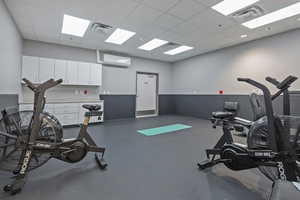 Exercise room featuring a drop ceiling and a wall mounted mini split