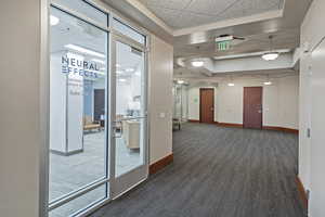 Hall featuring dark colored carpet and a drop ceiling