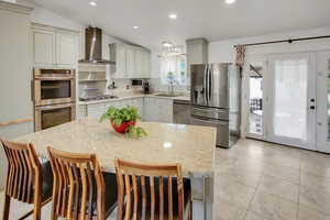 Kitchen with light stone counters, stainless steel appliances, a kitchen breakfast bar, vaulted ceiling, and backsplash