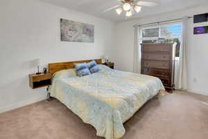 Carpeted bedroom with ceiling fan and baseboards