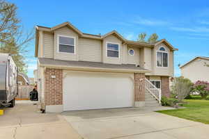 View of front of property featuring brick siding, concrete driveway, a garage, and roof with shingles