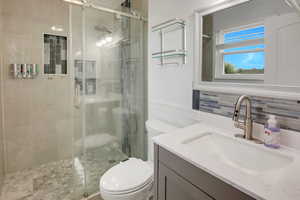 Bathroom featuring vanity, a stall shower, and wainscoting