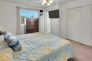 Bedroom featuring light colored carpet, a closet, and a ceiling fan