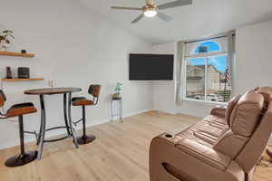 Living room with light wood-style floors, ceiling fan, and vaulted ceiling