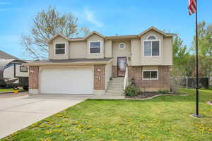 Split foyer home featuring brick siding, an attached garage, and concrete driveway