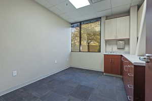 Unfurnished room featuring a drop ceiling and dark colored carpet