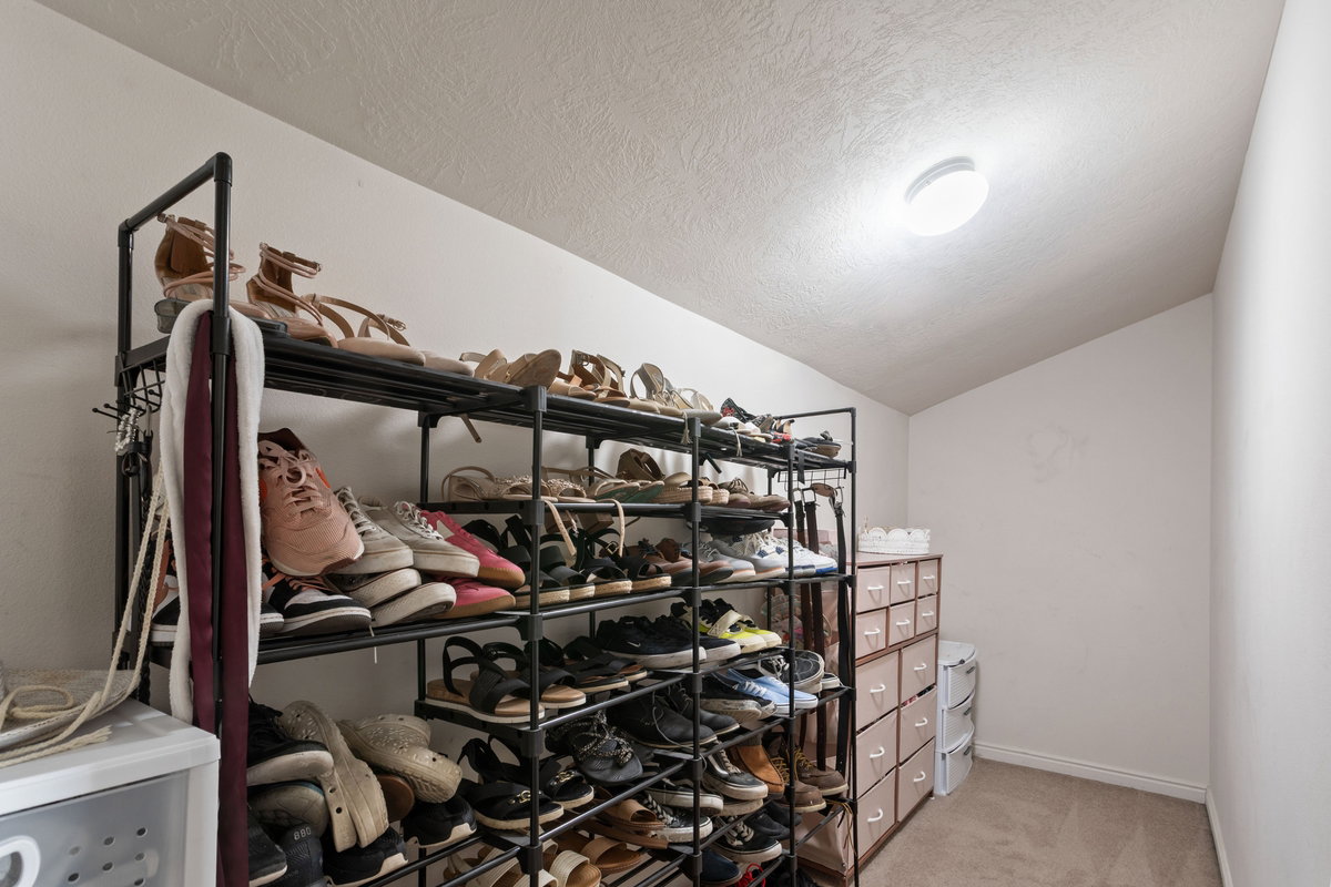 Walk in closet with lofted ceiling and light carpet