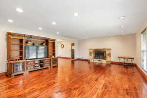 Living room with recessed lighting, wood-type flooring, and a stone fireplace