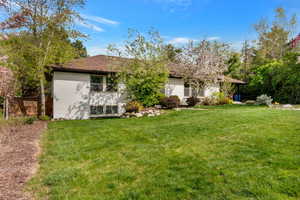 Rear view of property featuring a lawn and brick siding