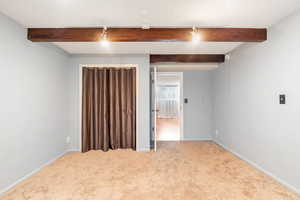 Spare room with a textured ceiling, beamed ceiling, carpet, and track lighting