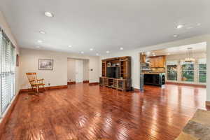 Living area with plenty of natural light, dark wood-style floors, and recessed lighting