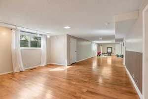 Below grade area featuring light wood-style flooring and a textured ceiling