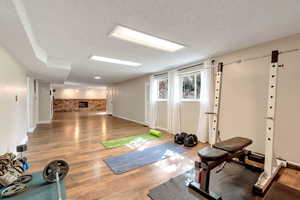 Exercise room with brick wall, wood finished floors, and a textured ceiling