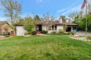 View of front of house featuring a garage, a chimney, stucco siding, and driveway