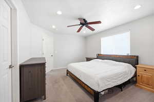 Carpeted bedroom with a ceiling fan and recessed lighting