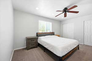 Carpeted bedroom with ceiling fan, multiple closets, and recessed lighting
