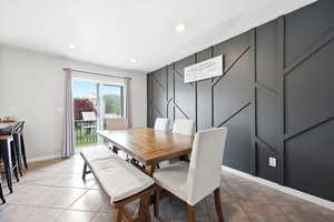 Dining room featuring light tile patterned floors, recessed lighting, and a decorative wall