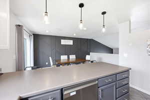 Kitchen featuring stainless steel dishwasher, light countertops, and hanging light fixtures