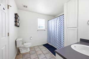 Full bath featuring a shower with shower curtain, vanity, and light tile patterned floors