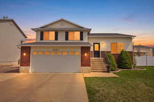 Tri-level home featuring brick siding, driveway, an attached garage, and a lawn