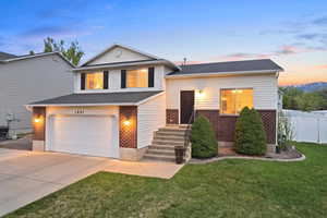 Split level home featuring brick siding, concrete driveway, and a garage