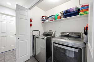 Laundry area with washing machine and dryer and tile patterned flooring