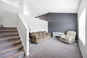 Carpeted living room with stairway and baseboards