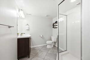 Bathroom featuring vanity, a stall shower, a textured ceiling, and light tile patterned floors