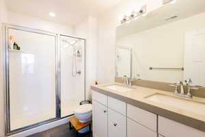 Bathroom with double vanity, a stall shower, and recessed lighting