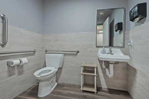 Bathroom featuring dark wood-style floors, tile walls, and a wainscoted wall