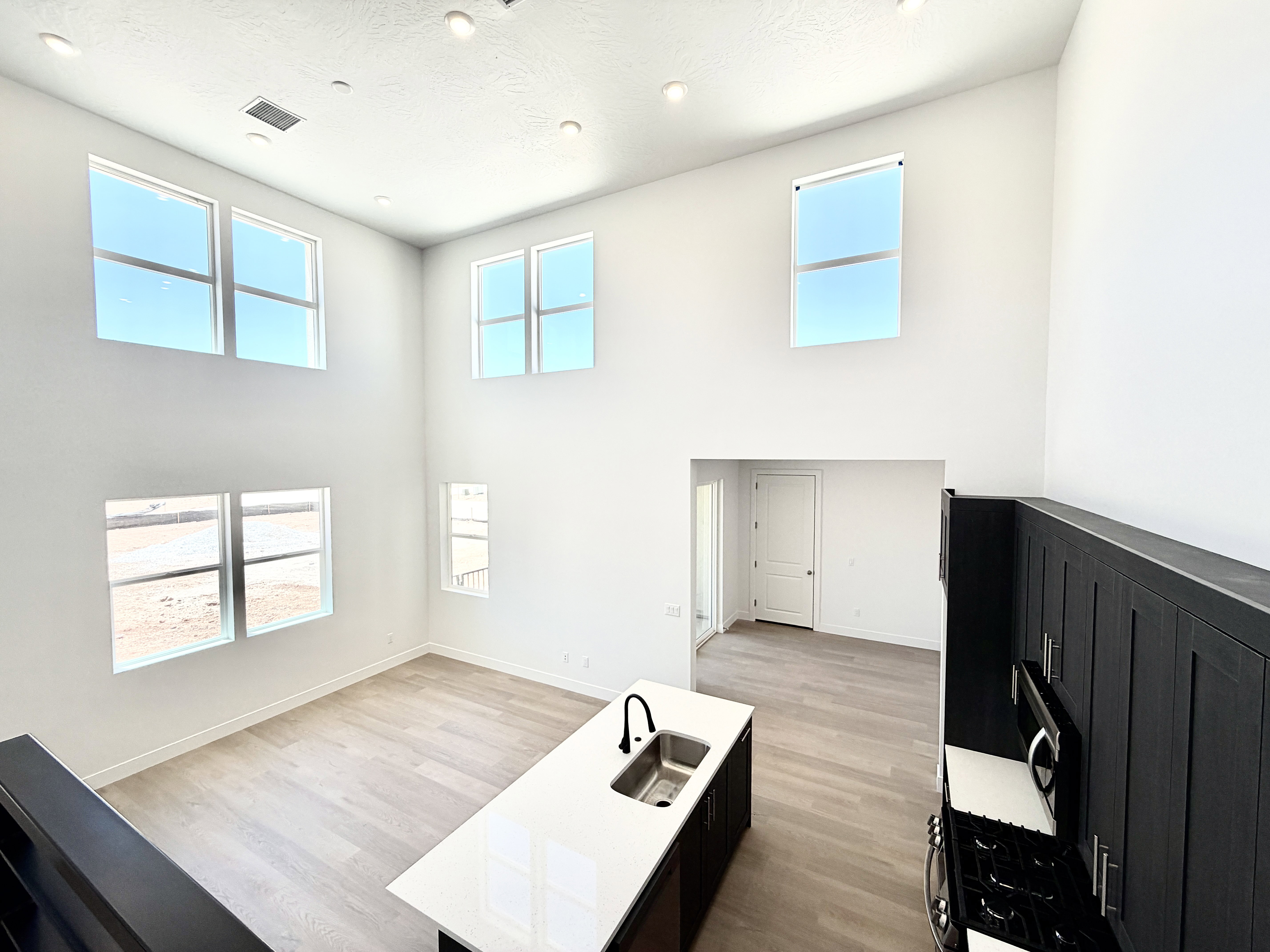 Two-story living area with multiple large windows, wood-finish flooring, and recessed lighting