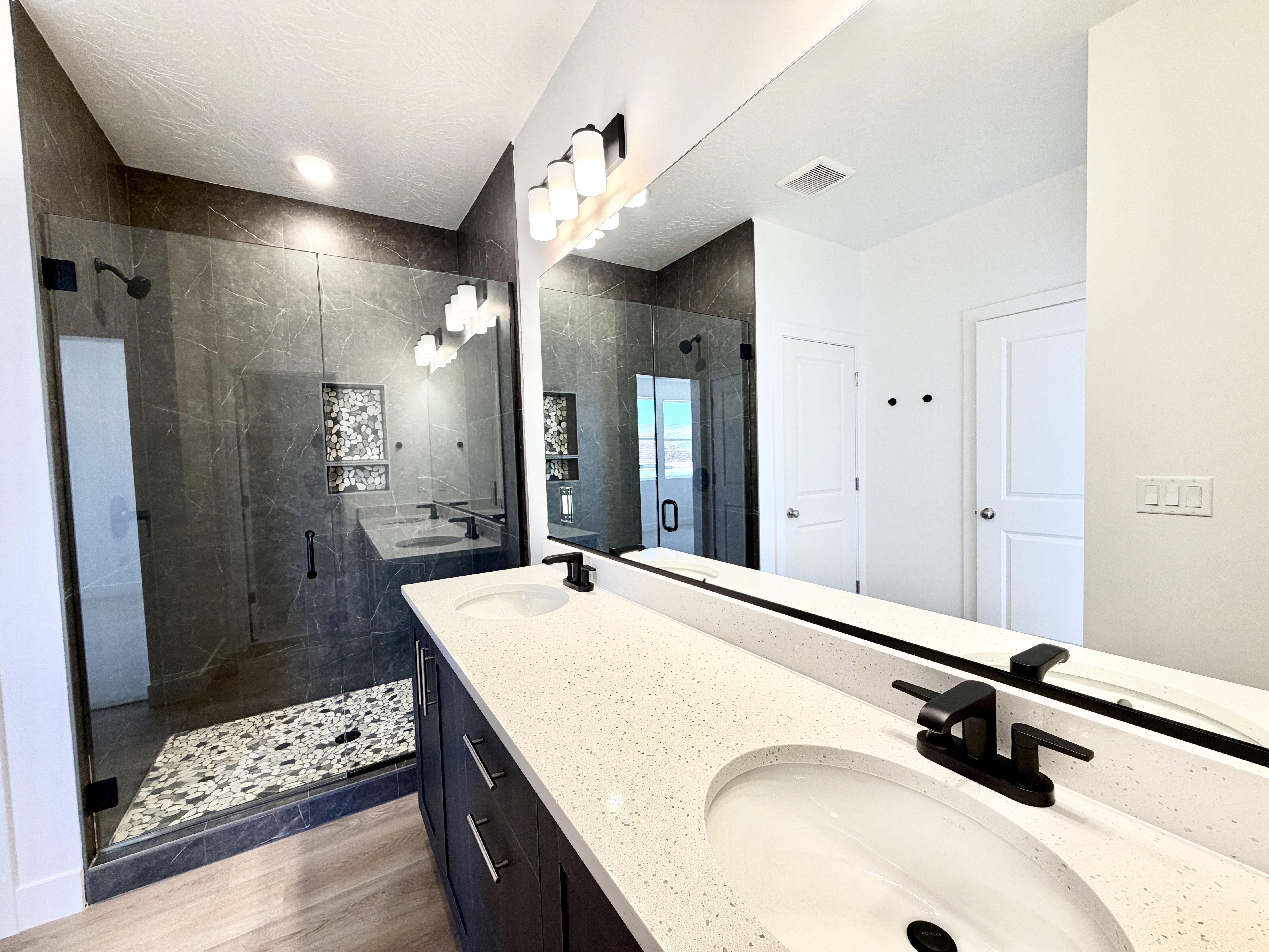 Contemporary bathroom featuring a dual vanity with white countertops, integrated sinks, and matte black faucets