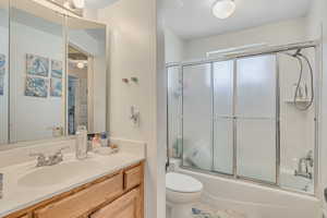 Full bath featuring vanity and bath / shower combo with glass door