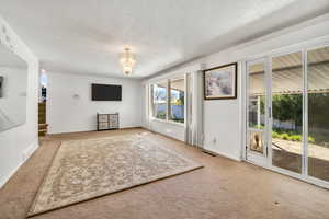 Unfurnished living room with a chandelier, a textured ceiling, and carpet